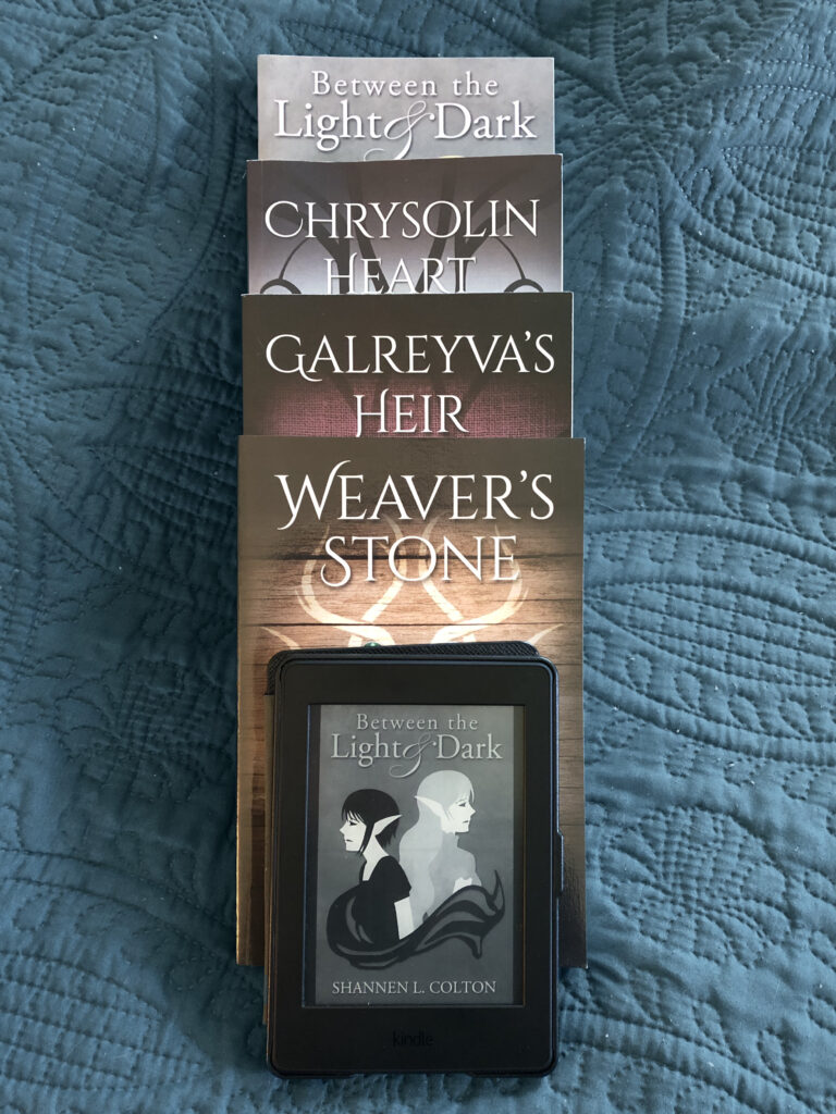 Photo of four books stacked along with a Kindle showcasing books by Shannen L. Colton.